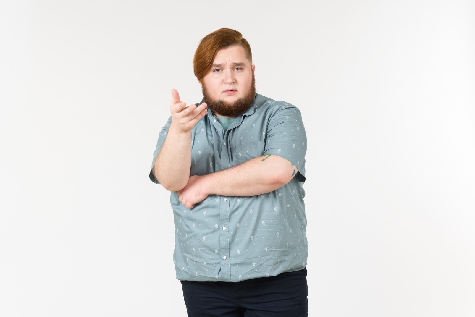 Pensive looking young overweight man standing with his hands crossed