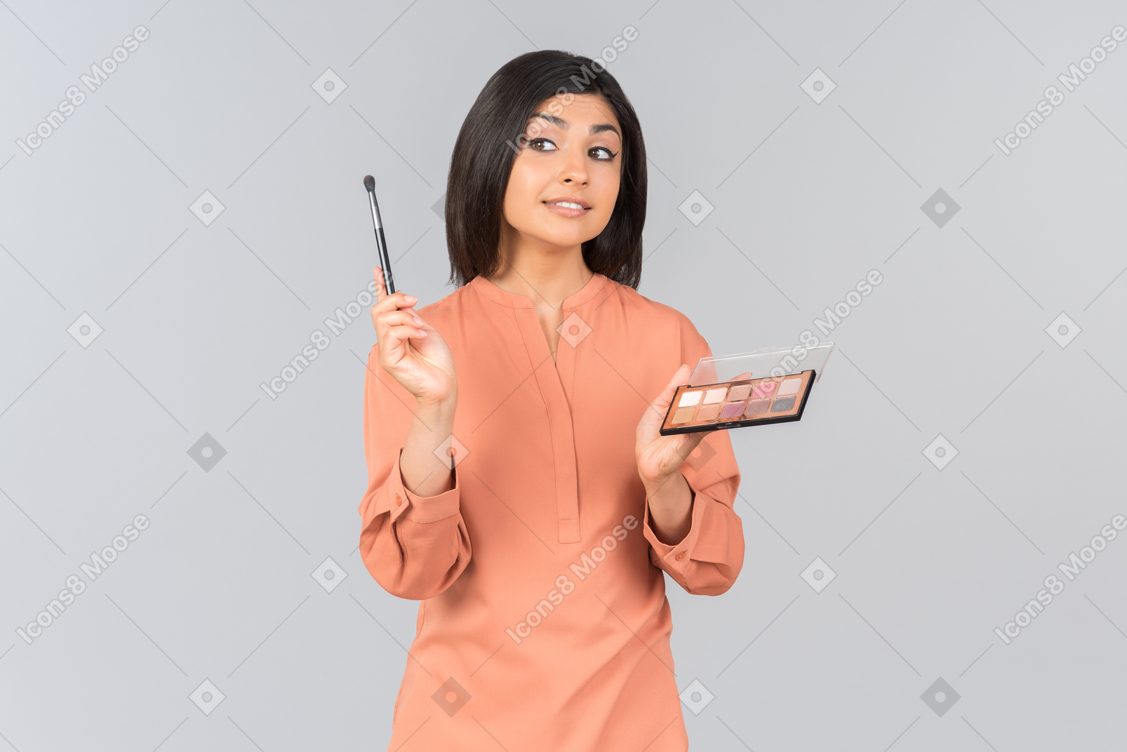 Indian woman holding eyeshadow and eye brush