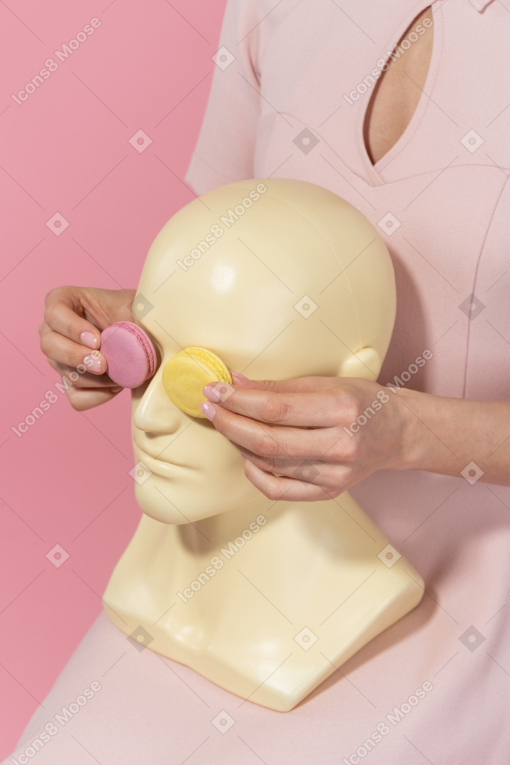 Coprendo gli occhi di un busto maschile con macarons