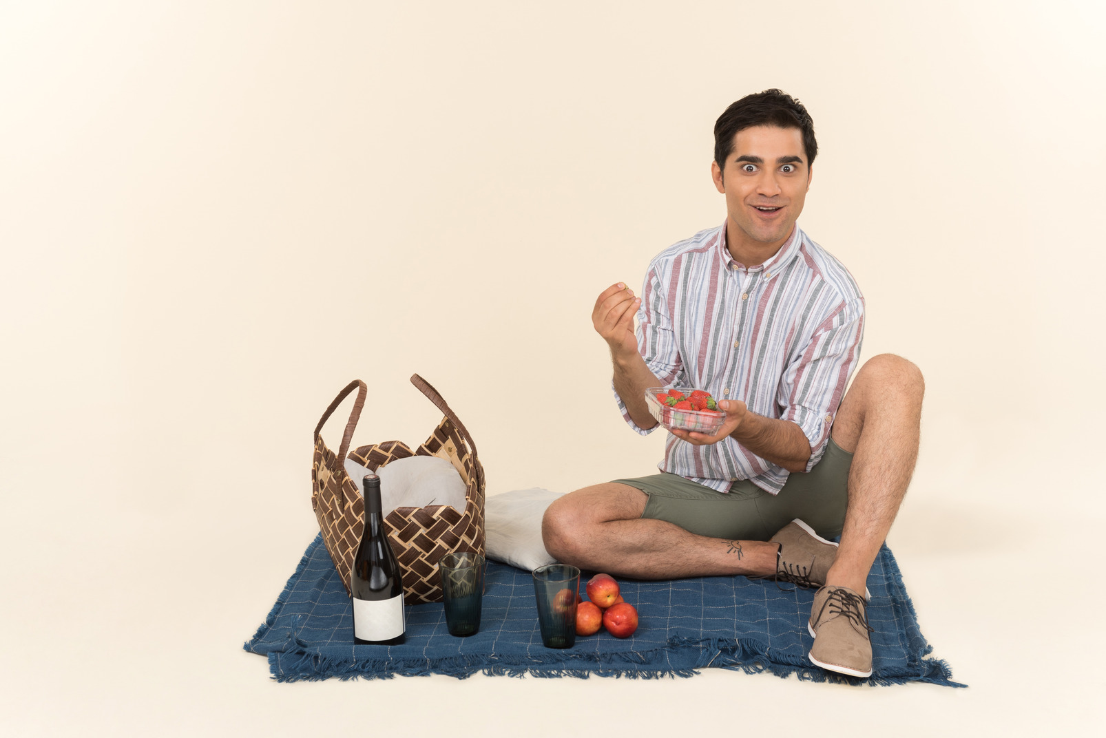 Excited young caucasian man eating fruits while having picnic