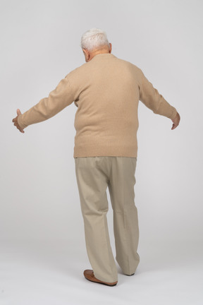 Vista posteriore di un vecchio in abiti casual in piedi con le braccia tese