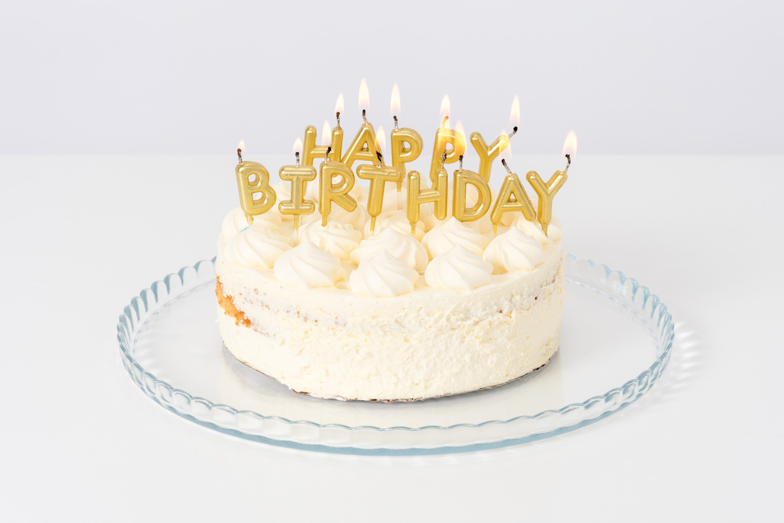 White cake with candles on a glass plate