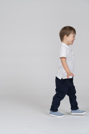 Side view of a smiling little boy walking