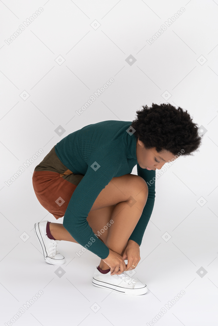 African-american teenager lacing up her white sneakers
