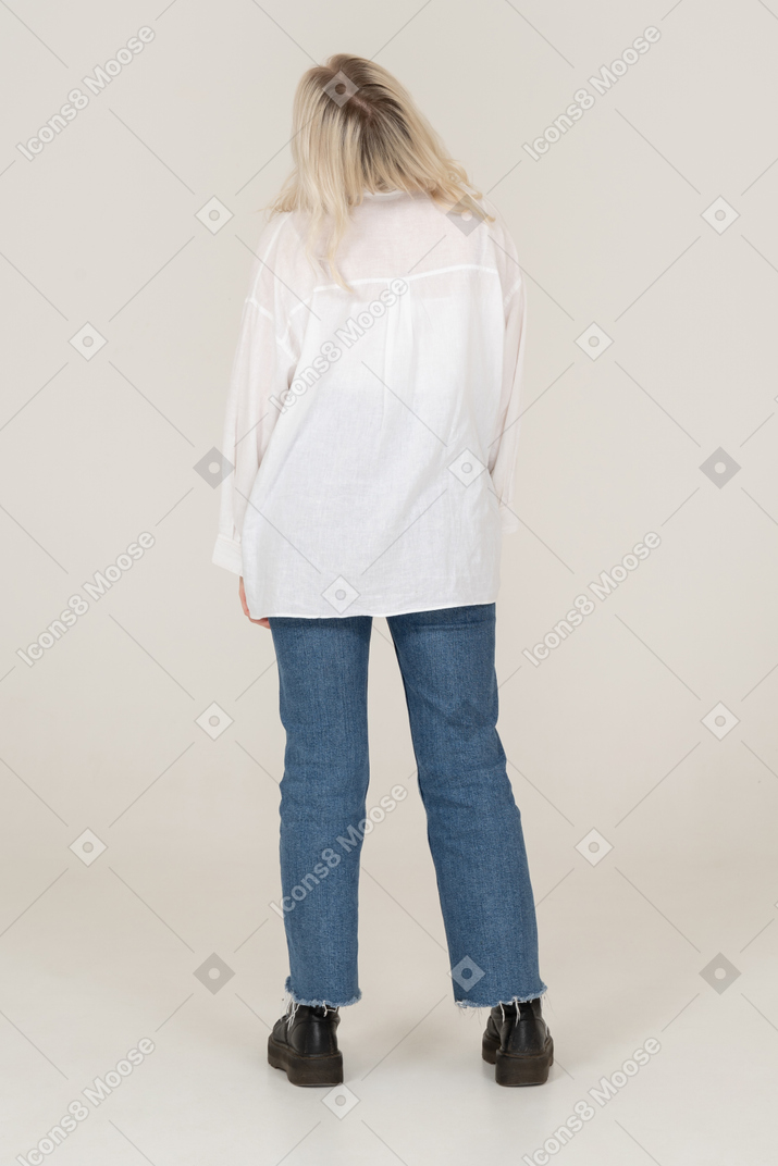 Back view of a blonde female in casual clothes standing still and throwing head back