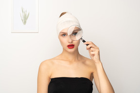 Young woman looking through magnifying glass