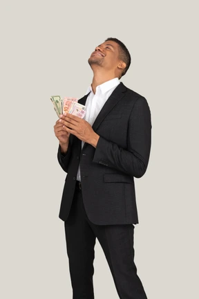 Three-quarter view of a young man in black suit holding banknotes