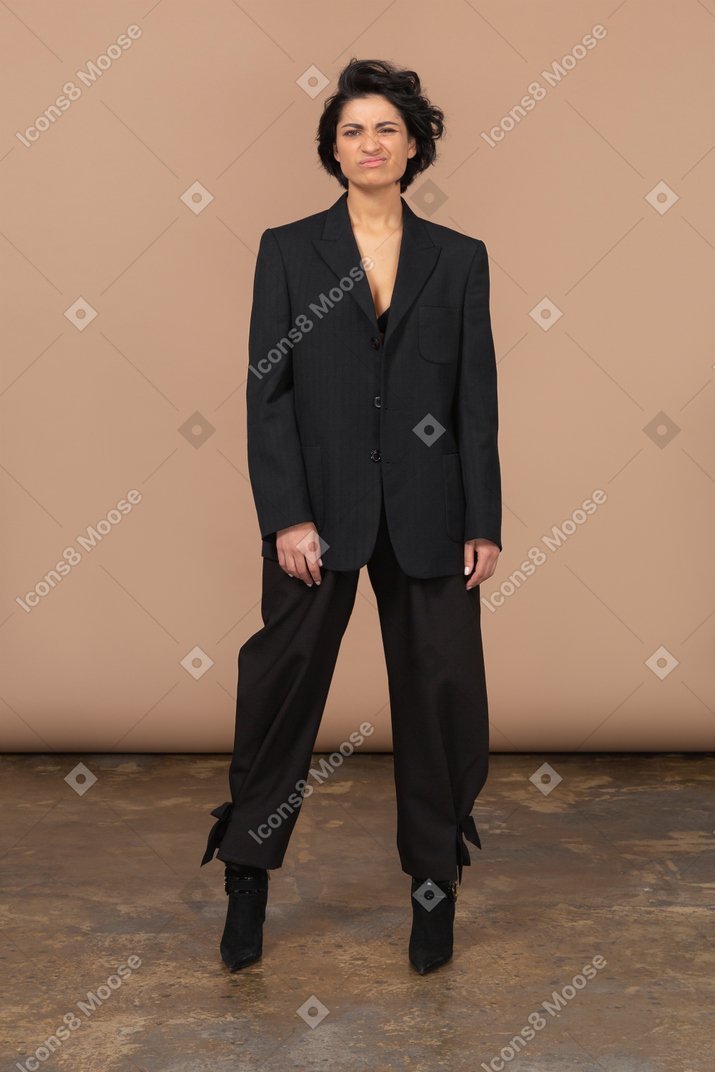 A woman standing in a room wearing a suit