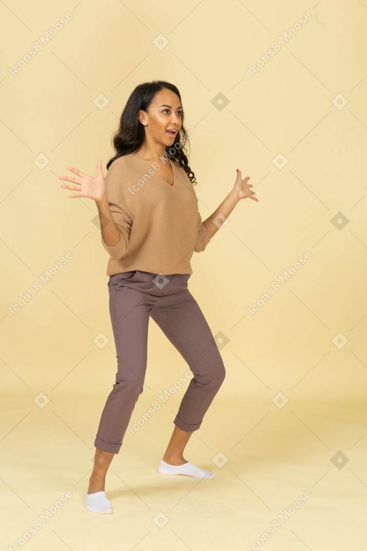 Three-quarter view of a funny dark-skinned young female outspreading her hands and legs