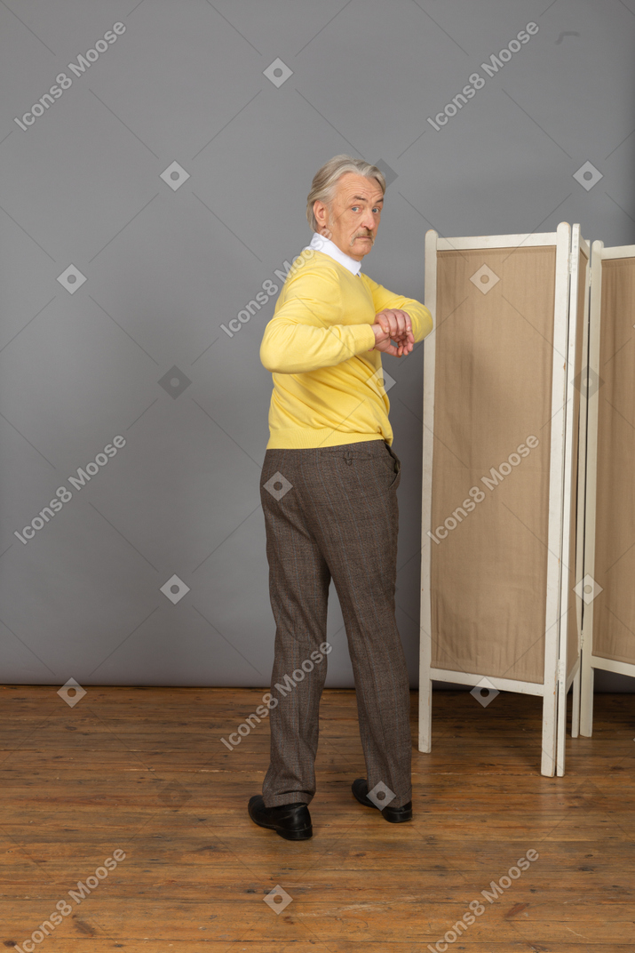 Back view of an old man exercising by making rotation