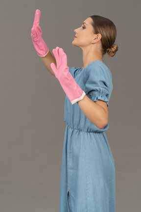 Vista laterale di una giovane donna che alza le mani mentre indossa i guanti