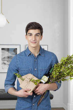 A man holding a bouquet of flowers and a bottle of wine