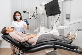 Comprimento total de uma dentista mostrando protótipo de dentes para paciente em um gabinete de hospital