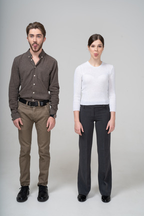 Front view of a young couple in office clothing showing tongue