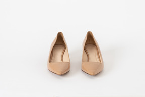 A front shot of a pair of beige lacquer court shoes