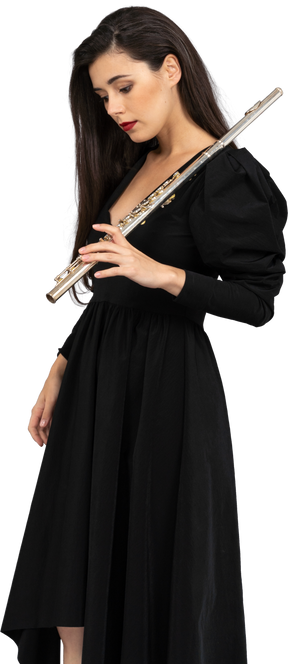 Vista di tre quarti di una giovane donna seria in abito nero, tenendo il flauto e guardando verso il basso