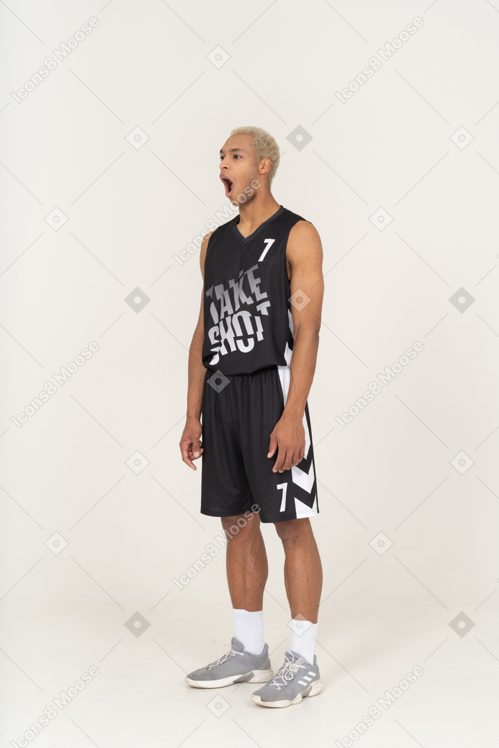 Vista di tre quarti di un giovane giocatore di basket che sbadiglia e che sta fermo