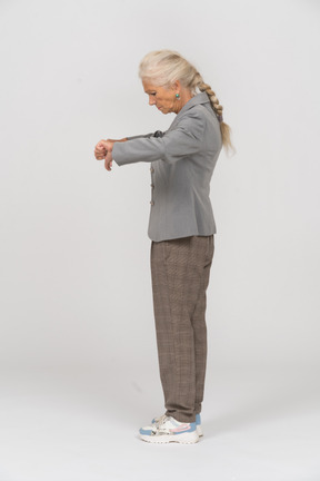 Vista lateral de una anciana en traje mostrando los pulgares hacia abajo