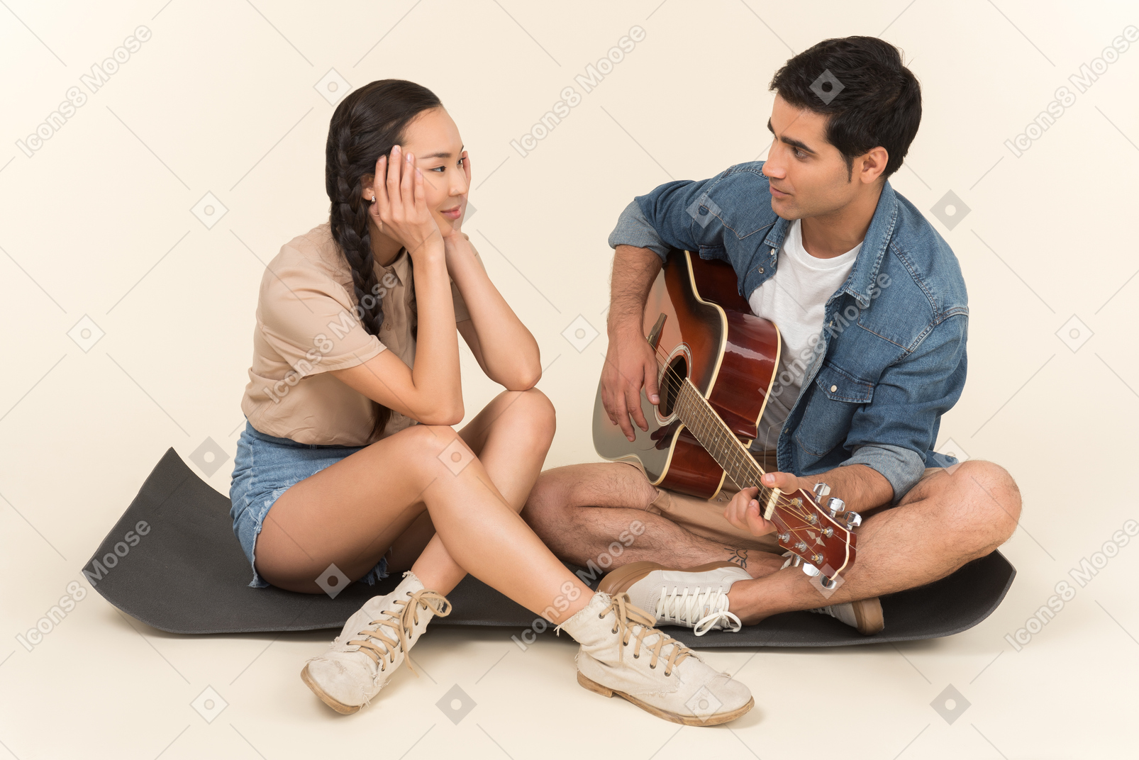 Karimat에 아시아 여자 근처에 앉아 기타를 연주하는 젊은 백인 남자
