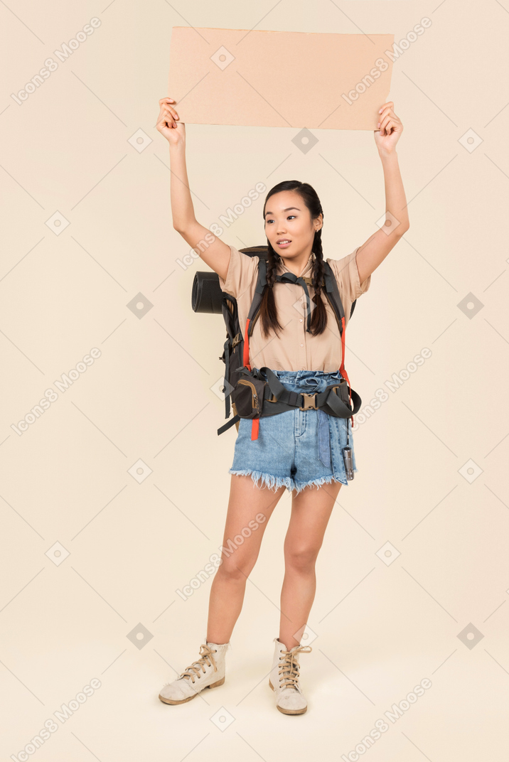 Young female hitchhiker holding up paper card