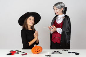 Ragazzo in costume da vampiro che mostra caramelle a sua mamma in costume da gatto