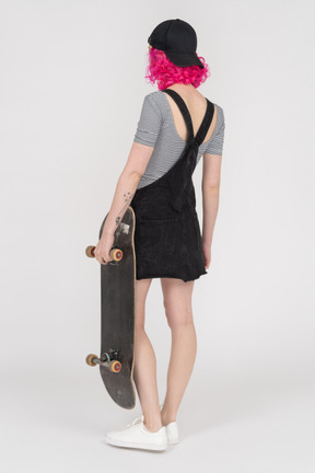 Ragazza irriconoscibile in posa con uno skateboard in mano