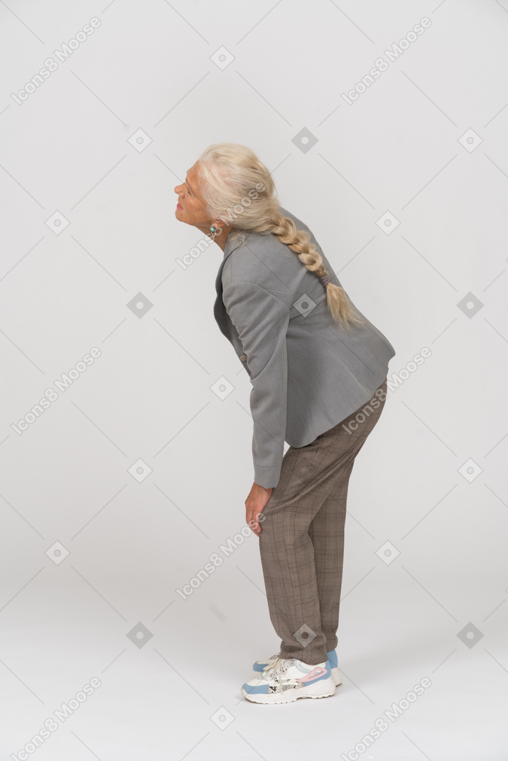 Side view of an old lady in suit touching her hurting knee