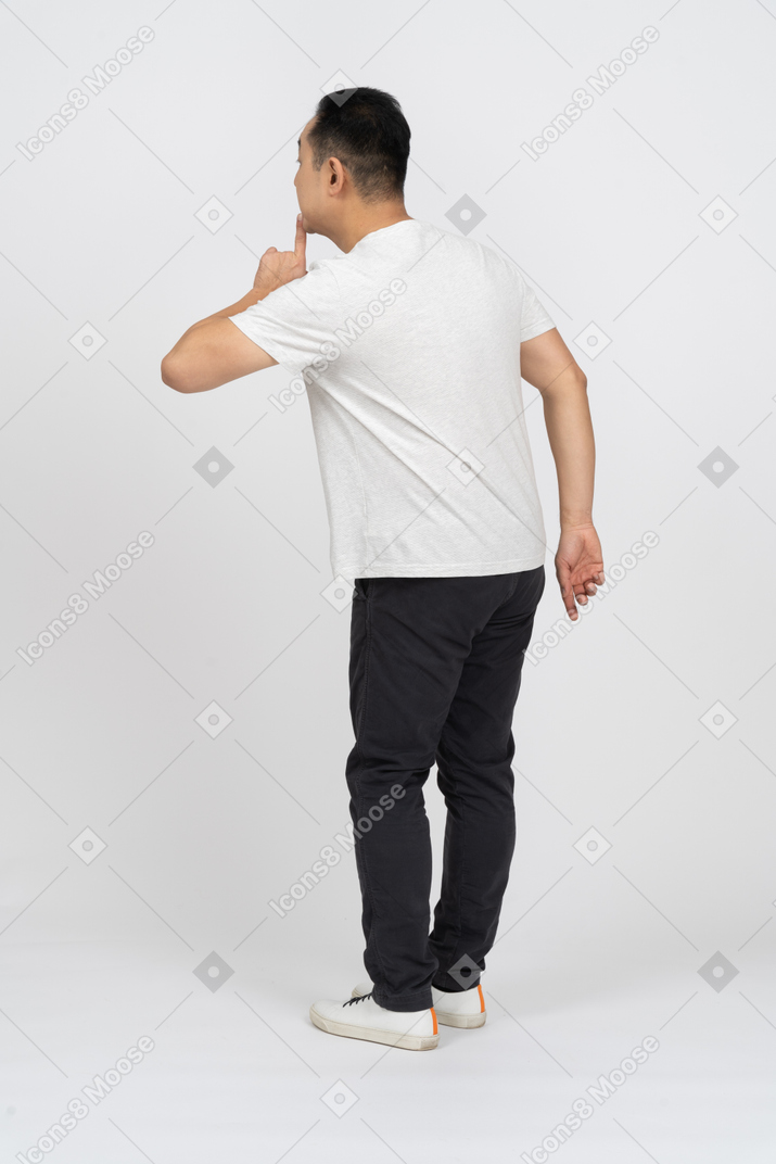 Side view of a man in casual clothes making hush gesture