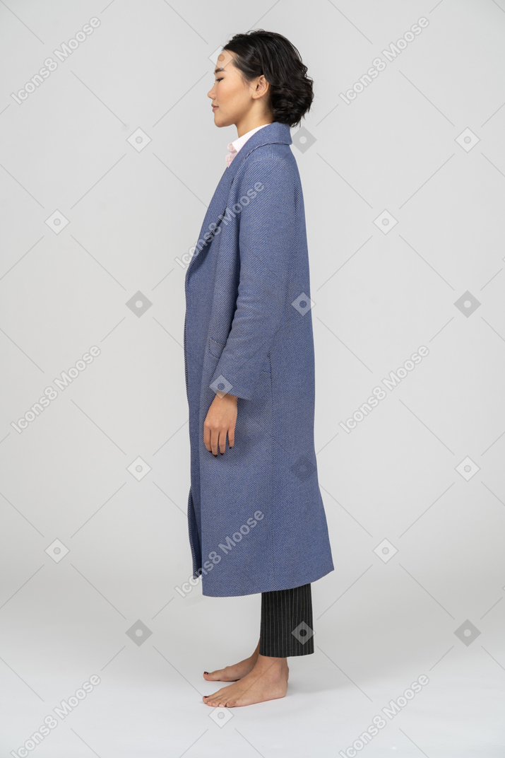 Vista lateral de uma mulher com os olhos fechados, vestindo casaco azul