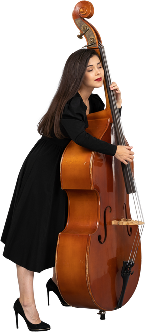 Vue latérale d'une jeune musicienne en robe noire tenant sa contrebasse