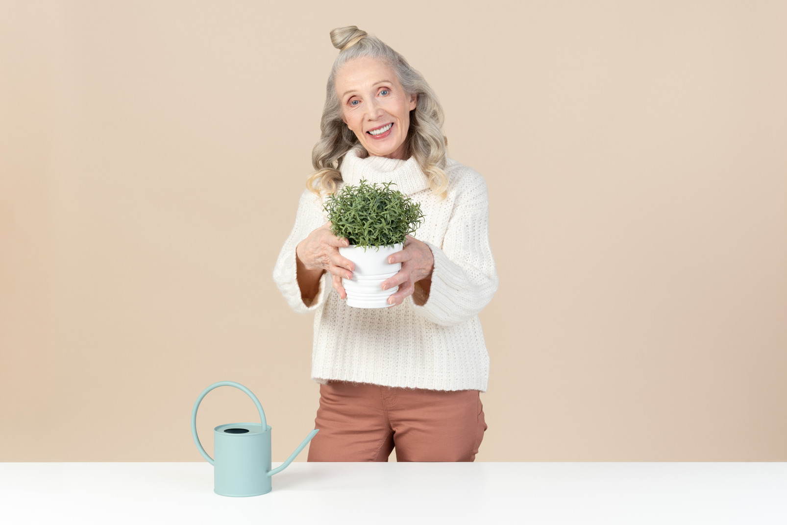 Old woman holding a green plant in pot
