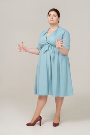 Vista laterale di una donna in abito blu in piedi con le braccia aperte