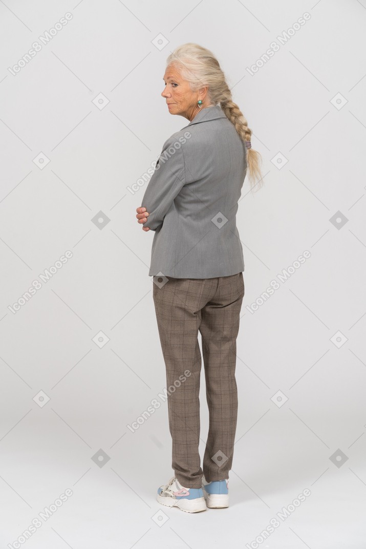 Rear view of an old lady in suit standing with crossed arms