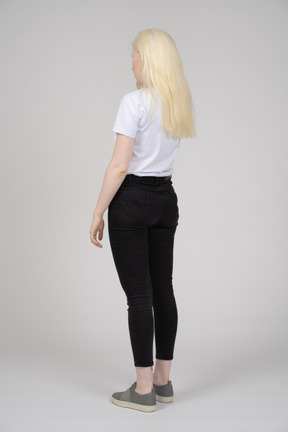 Back view of a blonde woman standing with arms at sides