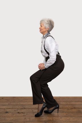 Vue latérale d'une femme en tenue de bureau faisant un demi-squat