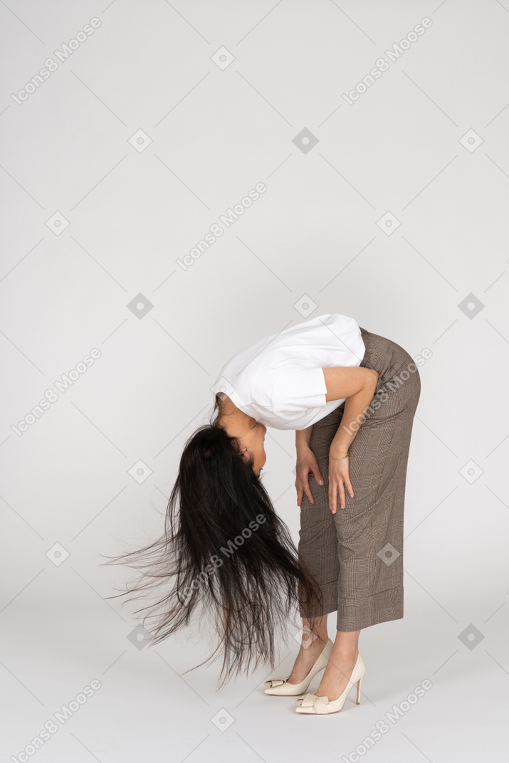一位年轻的女士，穿着马裤和t恤，凌乱的头发弯下腰，四分之三的视图