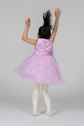 Back view of a girl in pink dress waving