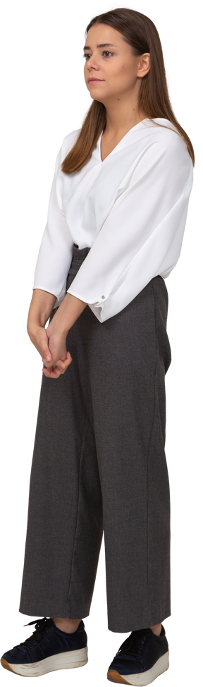 Three-quarter view of a young lady in office clothing holding hands together