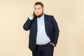 Serious looking young overweight office worker talking on the phone