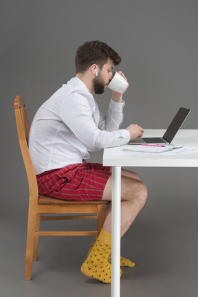 Büroangestellter trinkt kaffee, während er aus der ferne arbeitet