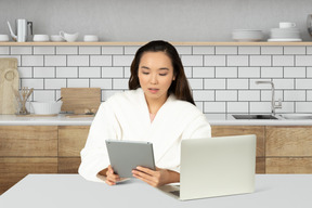 A woman sitting at a table using a tablet