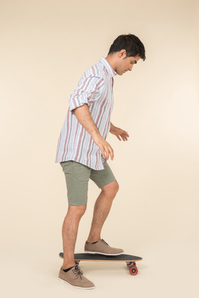 Young caucasian guy standing on skate in profile