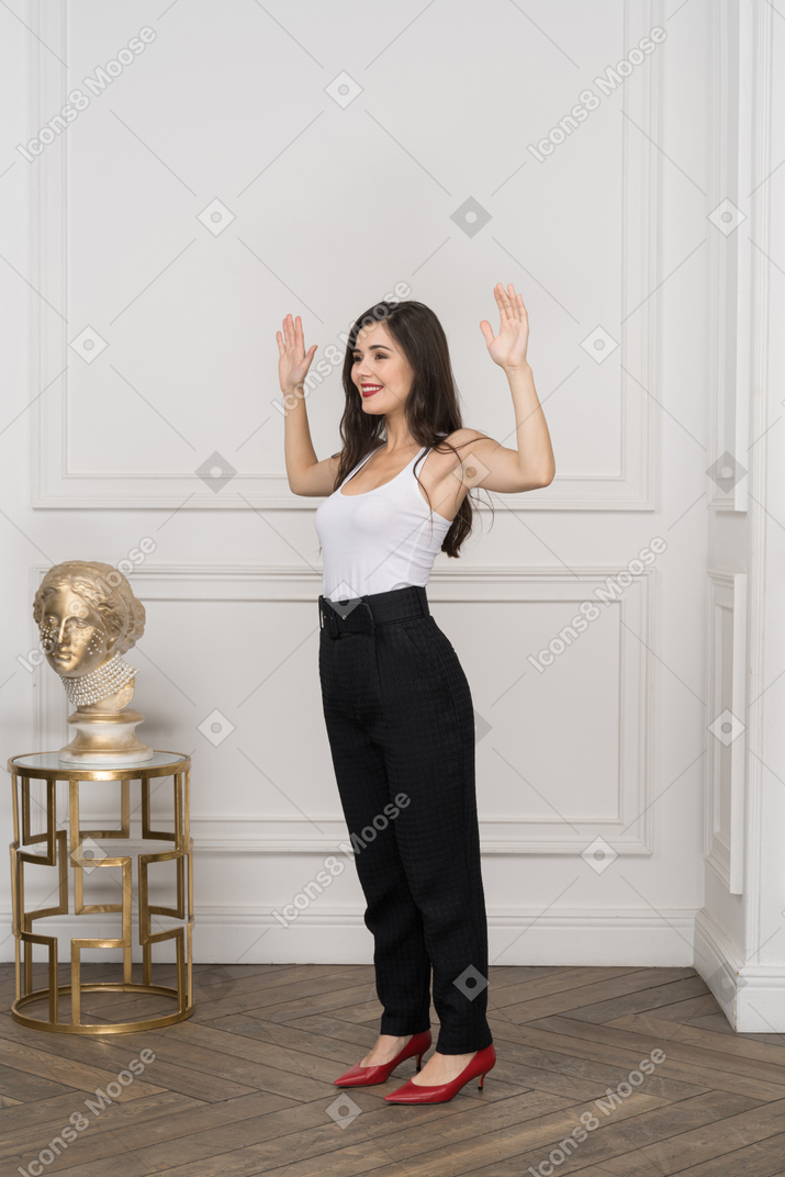 Вид в три четверти на молодую деловую женщину, поднимающую руки