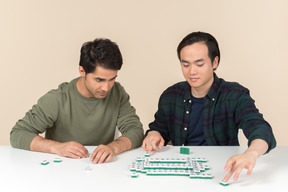 Interracial friends sitting at the table and playing board game