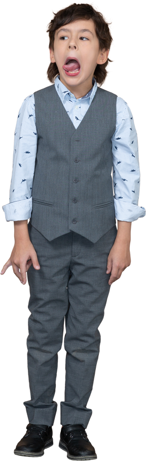 舌を示す灰色のスーツを着たかわいい男の子の正面図