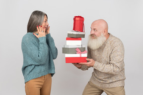 Aged man giving gifts to an elegant mature woman