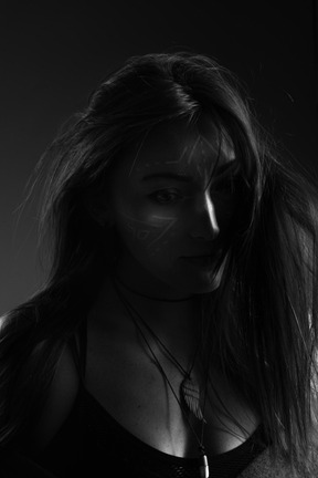 Dark silhouette of a young female with face art at lost