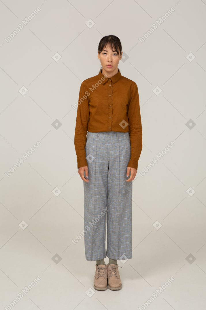 一位身着马裤和衬衫的年轻亚洲女性站着不动的前视图