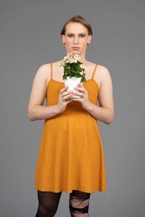 Portrait d'une jeune personne transgenre tenant un pot de fleurs