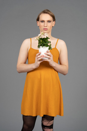 Portrait of a young transgender person holding pot of flowers